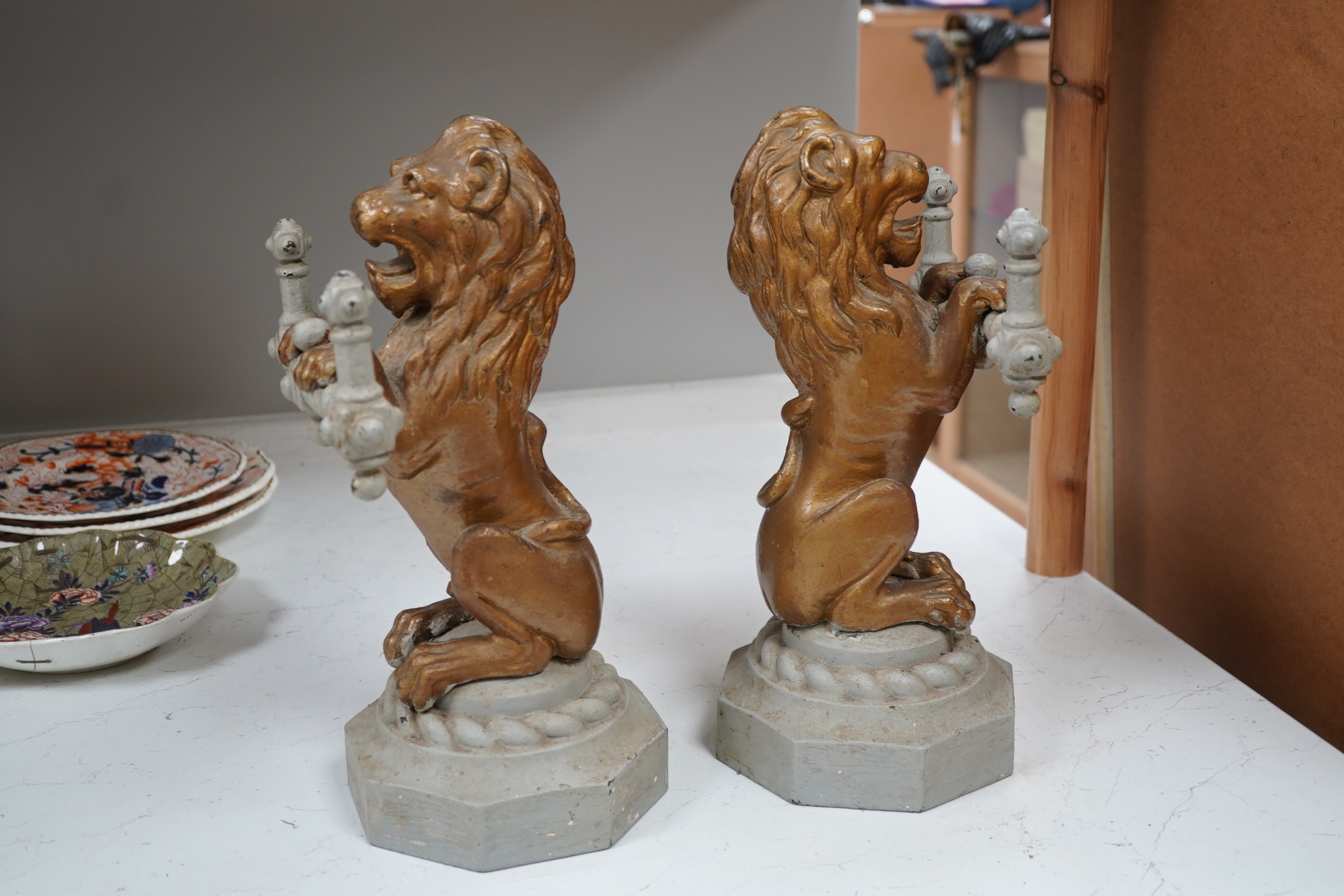 A pair of cast iron fire dogs in the form of triumphant lions, painted, 38cm high, 23cm wide. Condition - fair